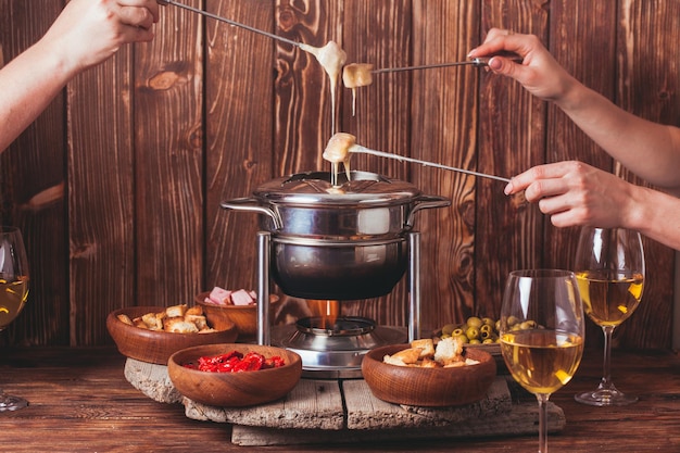 Délicieuse fondue au fromage sur une fourchette sur un support en bois