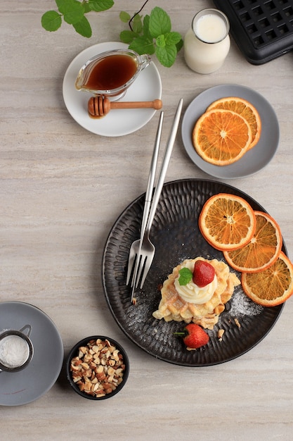 Délicieuse gaufre de croissant maison fraîchement cuite au four avec du sirop d'érable, des amandes hachées et des fraises.