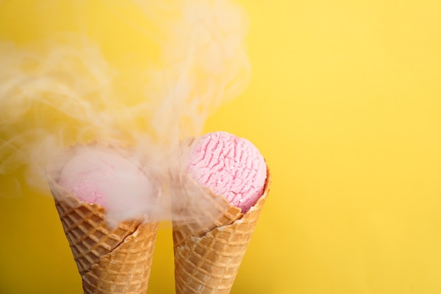 Délicieuse glace dans un cornet gaufré sur fond jaune couvert de fumée.