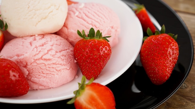 Délicieuse glace à la fraise avec des fraises fraîches sur une plaque blanche et noire. Savoureux dessert froid d'été.