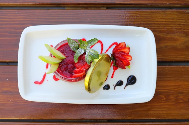 Une délicieuse panna cotta avec des coulis de fraises et des baies fraîches sur fond de bois