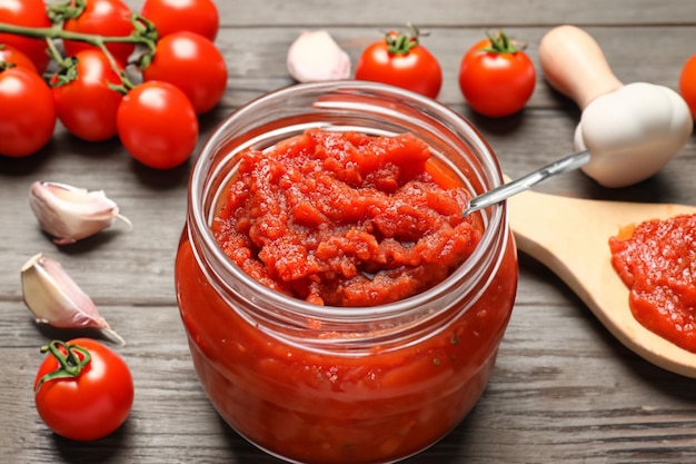 Délicieuse pâte de tomate en pot avec des ingrédients sur fond de bois