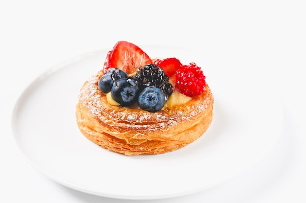 Photo une délicieuse pâtisserie à la crème et aux baies sur une assiette blanche