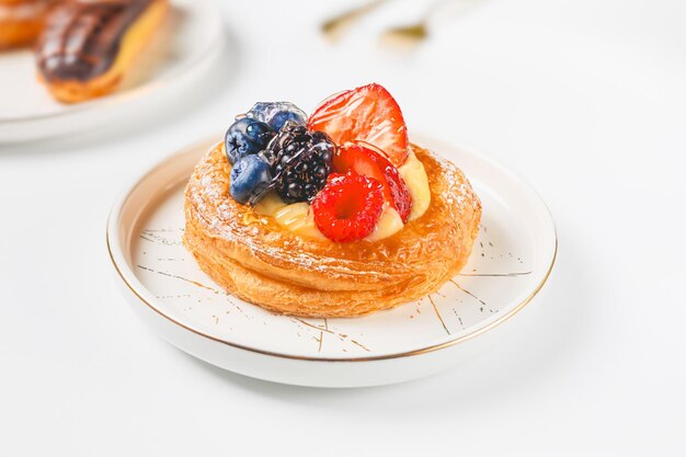 Photo une délicieuse pâtisserie à la crème et aux baies sur une assiette blanche