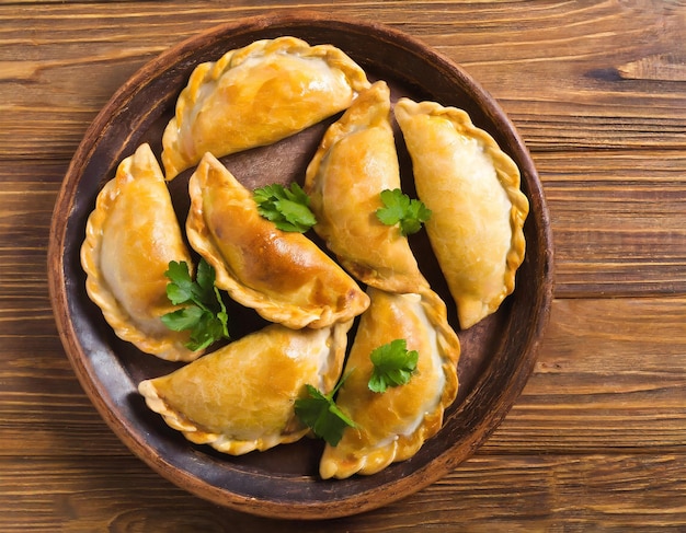 Délicieuse pâtisserie indienne samosa présentée sur une assiette avec des tomates et de la laitue sur une table en bois