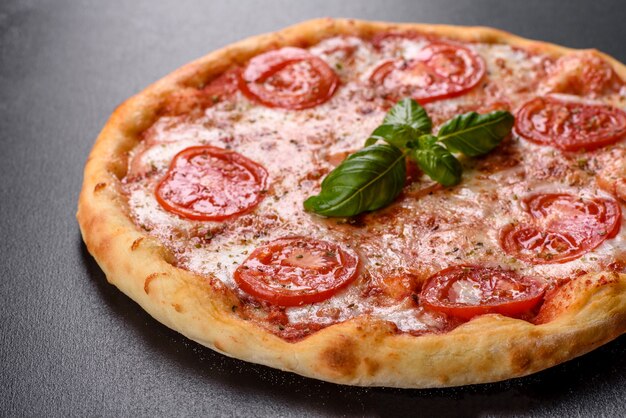 Photo délicieuse pizza au four avec tomates, fromage et basilic sur un fond de béton