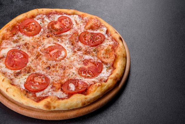 Délicieuse pizza au four avec tomates, fromage et basilic sur un fond de béton