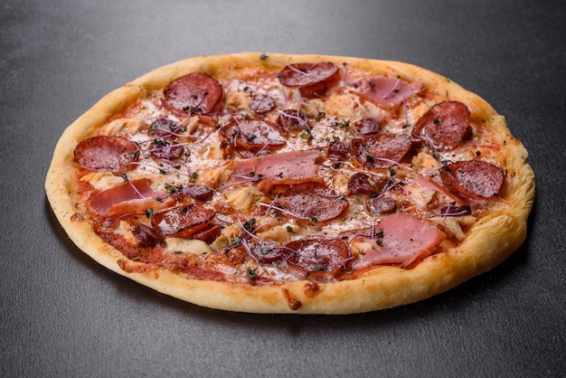 Délicieuse pizza au four avec tomates, salami et bacon sur un fond de béton foncé. cuisine italienne