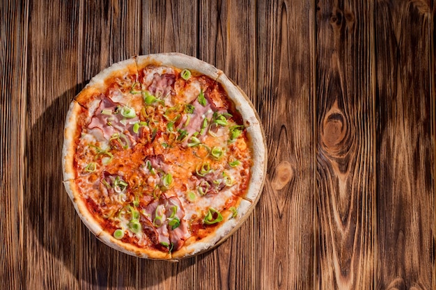 Délicieuse pizza au fromage mozzarella jambon poireaux sur une base de tomate sur fond de bois Espace de copie