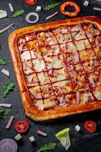 Une délicieuse pizza au pain plat à croûte carrée avec bacon et fromage. Pizza italienne fraîche maison Margherita aux olives et poivrons rouges sur fond sombre