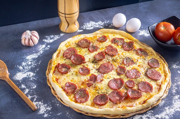 Photo délicieuse pizza au pepperoni avec oeufs blé ail tomate et fromage sur fond sombre