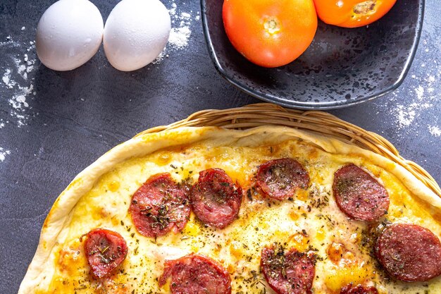 Photo délicieuse pizza au pepperoni avec oeufs blé ail tomate et fromage sur fond sombre