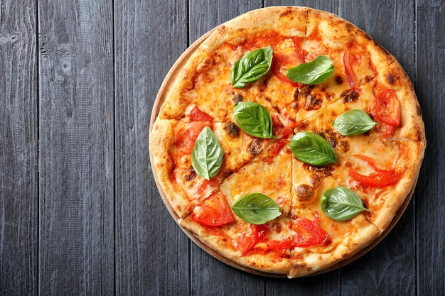 Délicieuse pizza aux tomates et basilic frais sur fond de bois