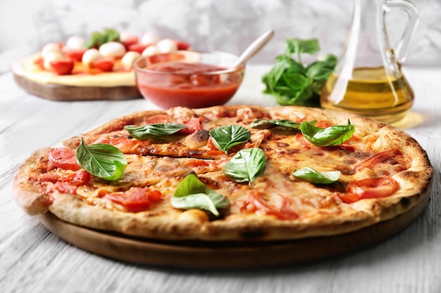 Délicieuse pizza aux tomates et basilic frais sur la table de cuisine