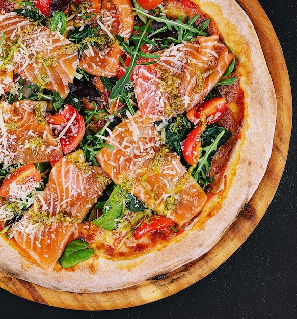 Délicieuse pizza chaude au saumon fromage tomates et roquette