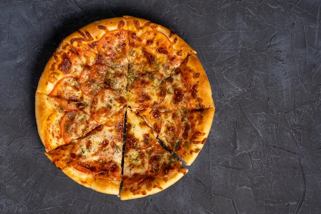 Délicieuse pizza chaude sur fond gris-noir Vue de dessus d'une délicieuse pizza chaude fraîchement cuite