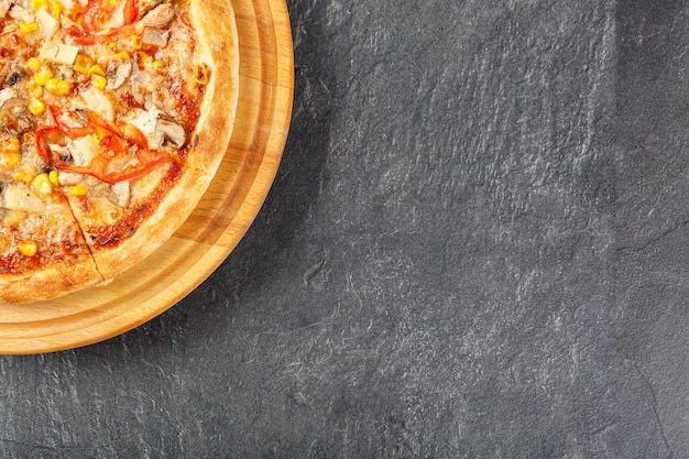 délicieuse pizza avec du poulet, des champignons, du fromage, des tomates et du maïs sur un fond de béton en gros plan