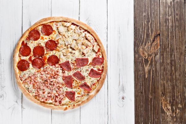 Délicieuse pizza fraîche 4 en 1 avec différents types de viande servie sur une table en bois. Vue de dessus.