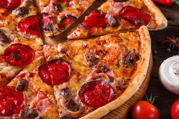 Délicieuse pizza fraîchement cuite en tranches avec bacon, viande, salami et fromage, gros plan. Cuisine traditionnelle italienne, restauration rapide.