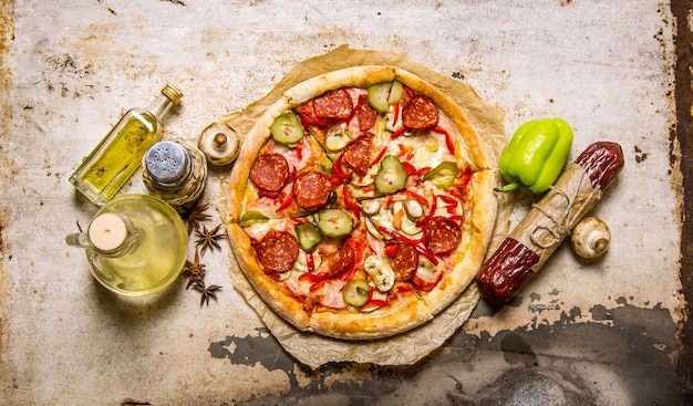 Délicieuse pizza avec des ingrédients - salami, poivrons, champignons et huile d'olive.