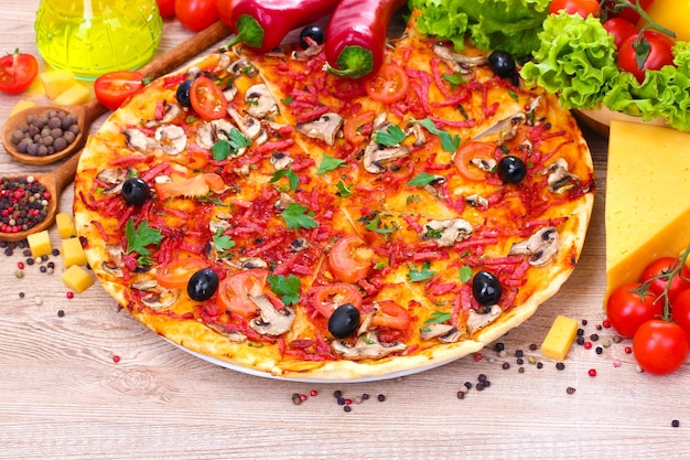 Photo une délicieuse pizza et des légumes sur une table en bois