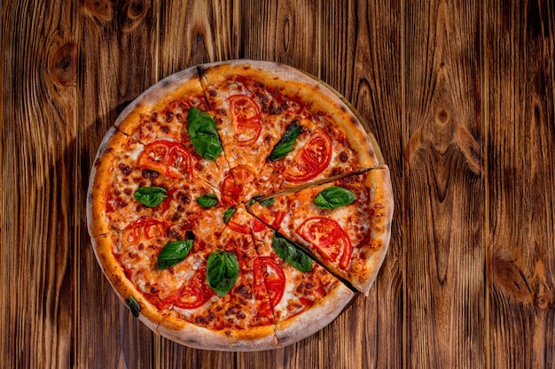 Délicieuse pizza Margherita parfumée avec tomates mozzarella et basilic sur sauce tomate sur fond bois Espace de copie