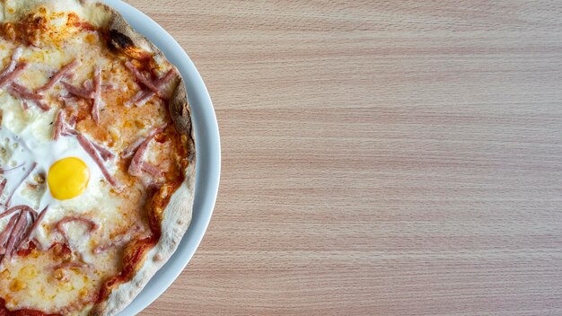 Délicieuse pizza avec œuf sur table en bois vue de l'espace pour le texte