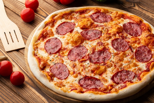 Délicieuse pizza Pepperoni maison chaude sur la table en bois. Pizza au pepperoni - Pizza maison fraîche avec pepperoni, fromage et sauce tomate sur fond de pierre noire rustique avec espace copie.