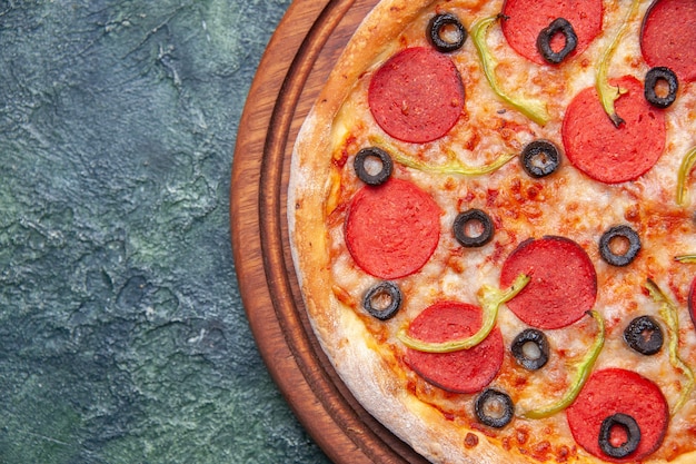 Délicieuse pizza sur une planche à découper en bois sur le côté gauche sur une surface sombre isolée avec un espace libre en gros plan