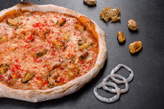 Photo une délicieuse pizza en tranches avec des fruits de mer et des tomates sur fond noir.