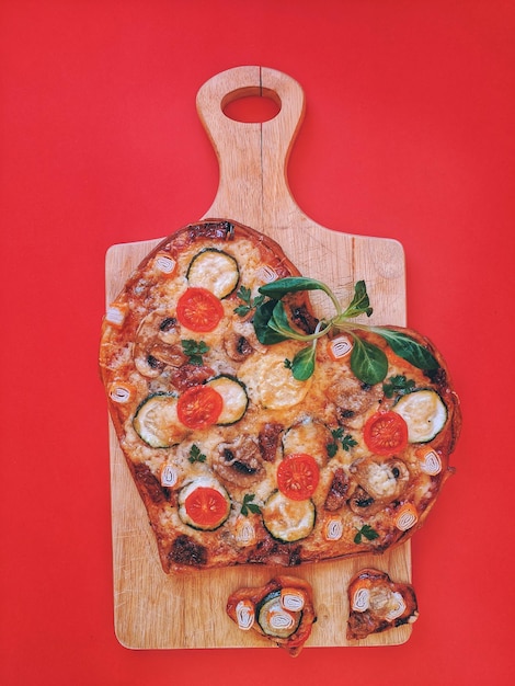 Photo une délicieuse pizza végétarienne en forme de cœur avec des tomates, des légumes et du fromage pour la saint-valentin.