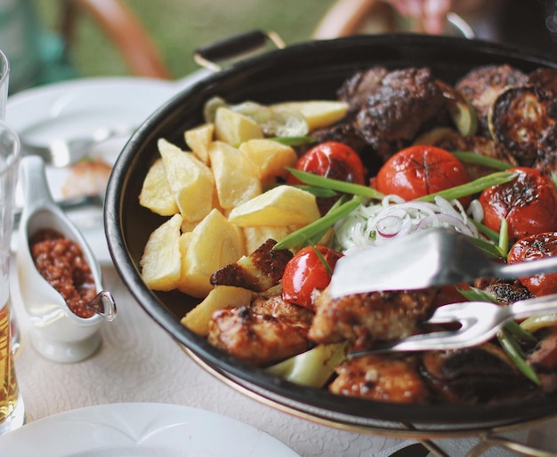 Photo délicieuse poêle à frire avec des légumes et de la viande. pommes de terre, tomates et sauce piquante. vue de dessus, à plat