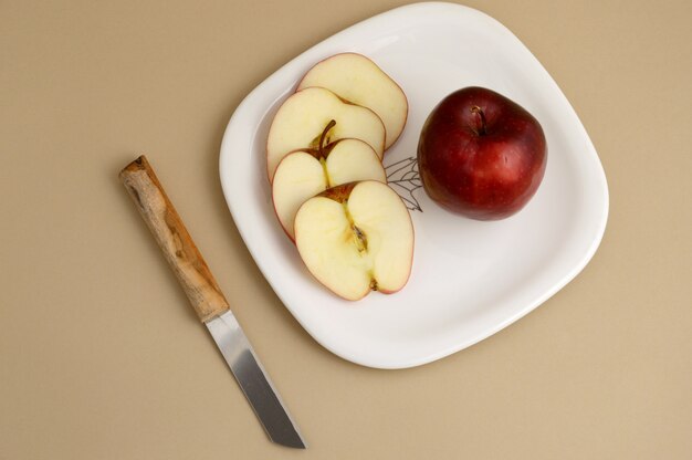 Délicieuse pomme et tranche en plaque blanche avec couteau et fourchette