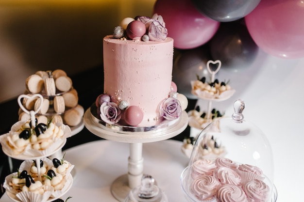 Délicieuse réception de mariage Gâteau d'anniversaire sur fond ballons décor de fête Espace de copie Concept de célébration Gâteau à la mode Barre de bonbons Table avec dessert bonbons bonbons