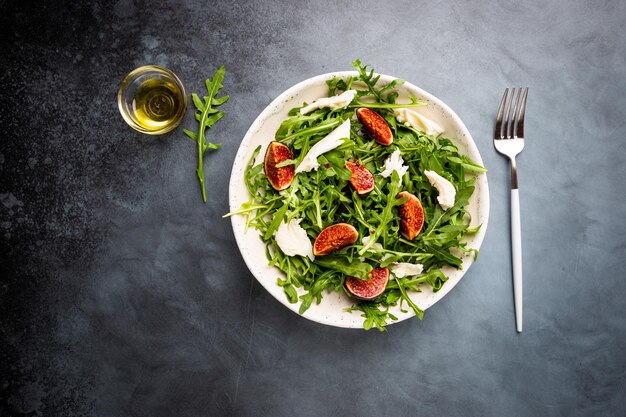 Délicieuse salade aux figues roquette et fromage de chèvre sur plaque blanche vue de dessus copie espace