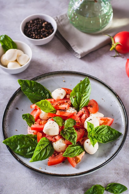 Délicieuse salade caprese avec tomates mûres, fromage mozzarella et basilic sur une assiette vue verticale