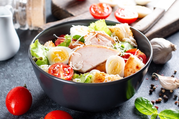 Une délicieuse salade césar au poulet avec du parmesan, de la vinaigrette et des croûtons sur fond sombre