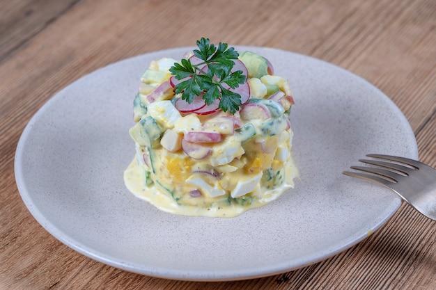 Délicieuse salade de concombre, radis et œuf à la coque avec sauce à la crème dans une assiette sur fond de bois. Alimentation saine, gros plan