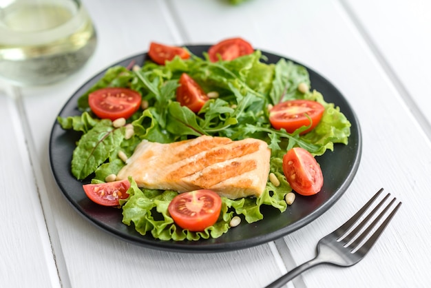 Délicieuse salade fraîche avec du poisson, des tomates et des feuilles de laitue. La nourriture saine