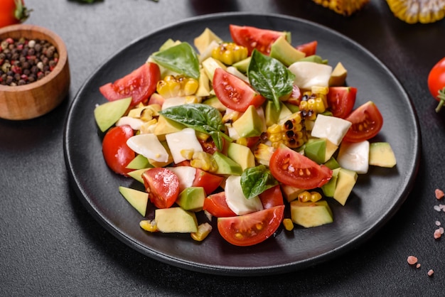 Délicieuse salade fraîche avec tomates, avocat, fromage et maïs grillé à l'huile d'olive. Cuisine méditerranéenne