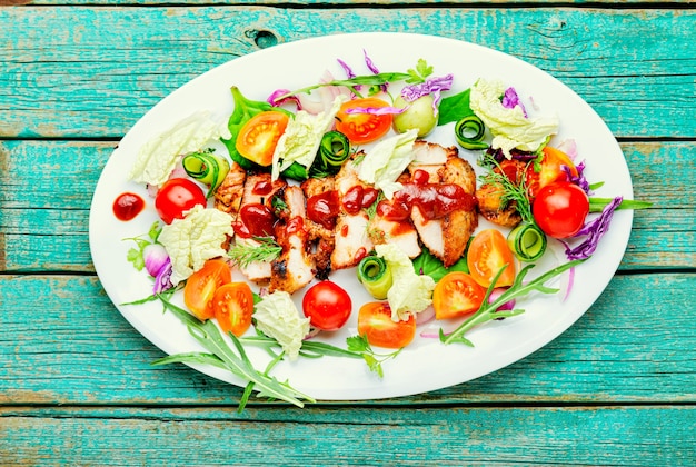 Délicieuse salade avec tomate, concombre, laitue et steak de viande. Salade saine sur plaque blanche