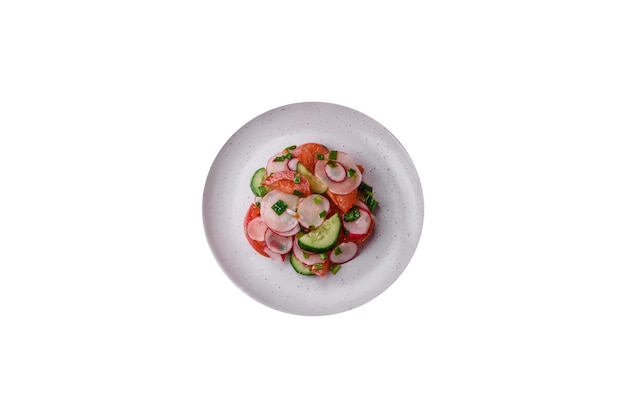 Délicieuse salade végétalienne de légumes frais de tomates, concombres et radis avec sel et épices sur fond de béton foncé