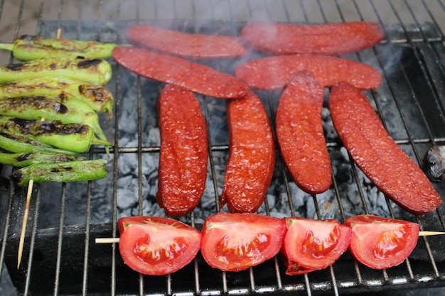 délicieuse saucisse grillée cuite au barbecue. tomates et poivrons.