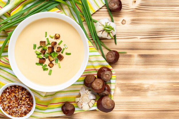 Délicieuse soupe aux marrons avec croûtons et herbes sur une table en bois. Vue de dessus. Copiez l'espace.