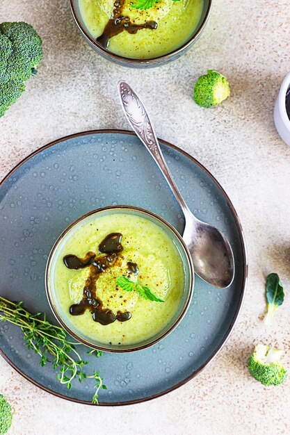 Photo délicieuse soupe à la crème de brocoli servie avec de l'huile épicée et de la menthe. plat végétarien.