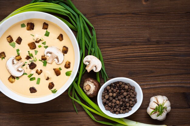 Délicieuse soupe à la crème, faite de champignons avec des croûtons sur une table en bois. Vue de dessus. Copiez l'espace.