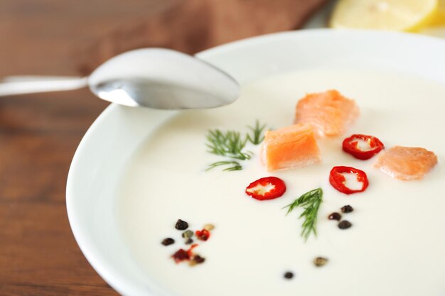 Délicieuse soupe à la crème de saumon avec une cuillère sur une table en bois se bouchent