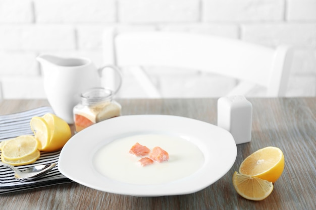 Délicieuse soupe à la crème de saumon dans une assiette blanche sur une table en bois se bouchent