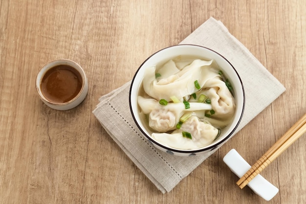 Délicieuse soupe Wonton (soupe de boulette) ou Pangsit Kuah servie dans un bol sur fond sombre.