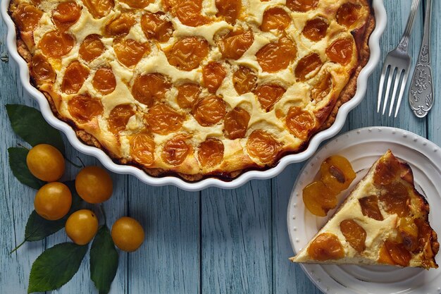 Délicieuse tarte aux prunes cerises sur une table en bois peinte en bleu